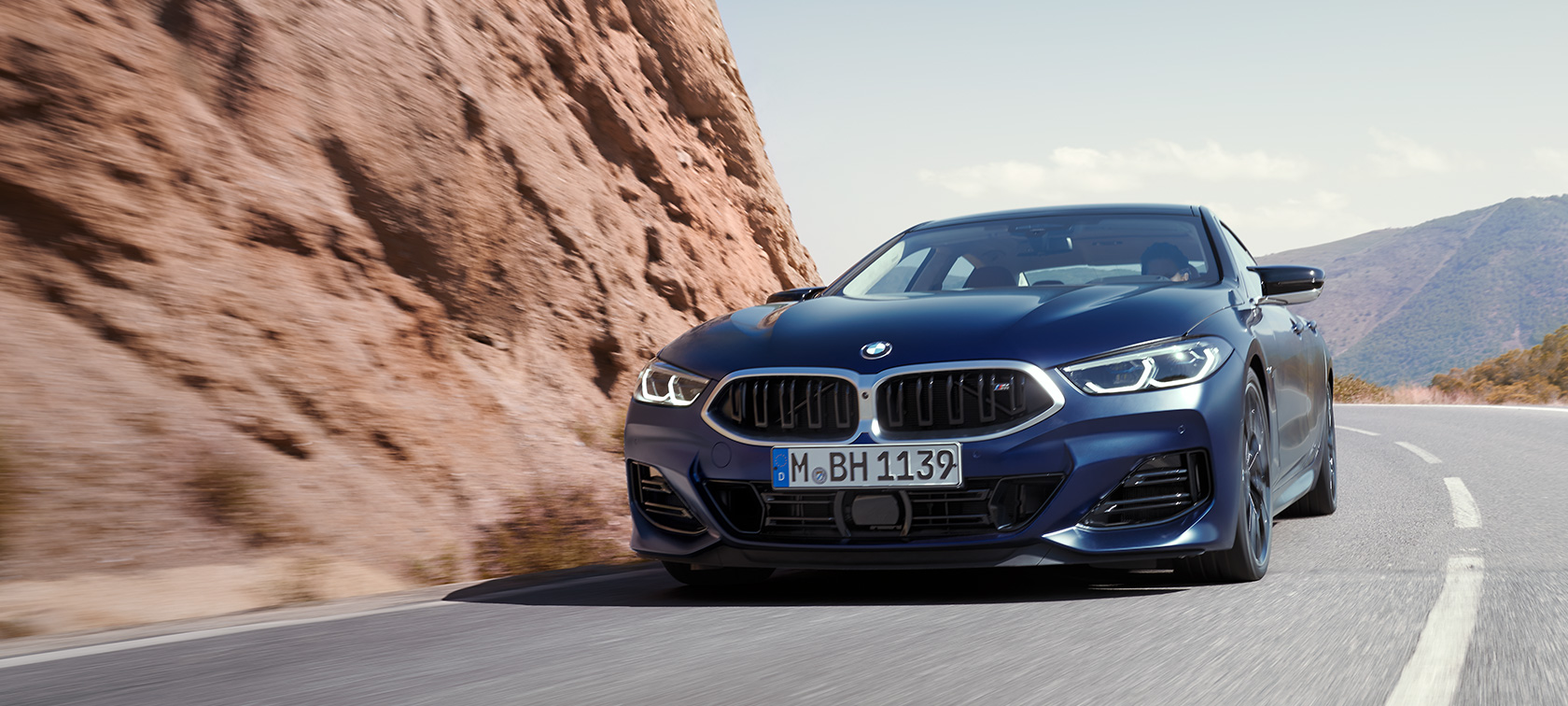 BMW 8 Series Gran Coupé G16 LCI Facelift 2022 BMW Individual Frozen Tanzanite Blue metallic three-quarter front view driving on a mountain road