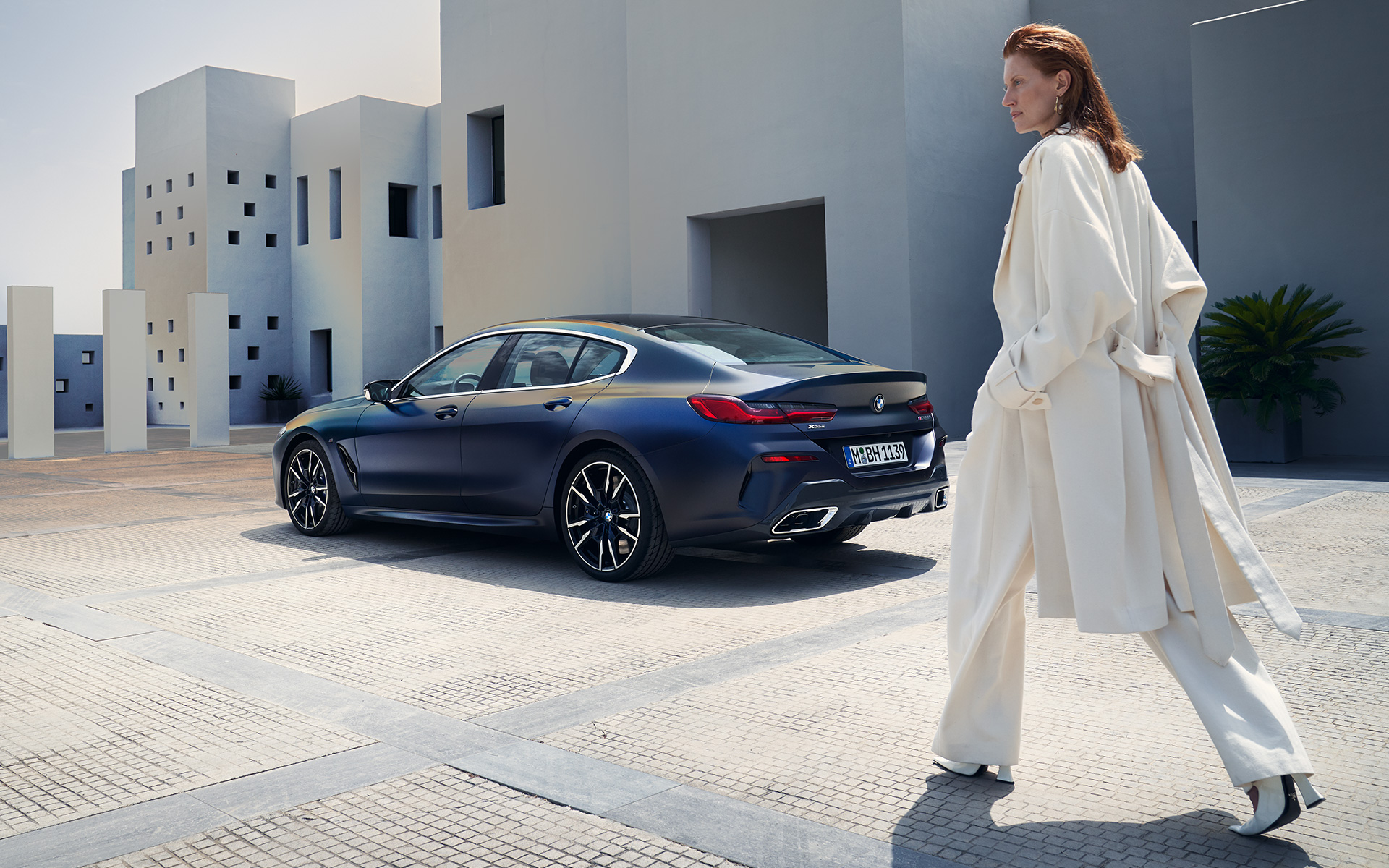 BMW M850i xDrive Gran Coupé G16 LCI Facelift 2022 BMW Individual Frozen Tanzanite Blue metallic three-quarter rear view with female model