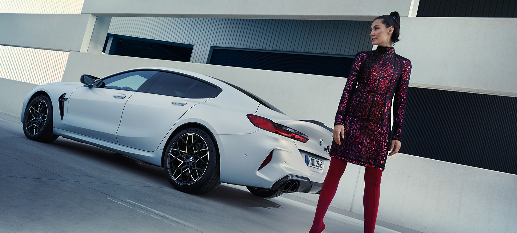 BMW M8 Competition Gran Coupé F93 LCI Facelift 2022 BMW Individual Frozen Brilliant White metallic three-quarter rear view with female model standing next to vehicle