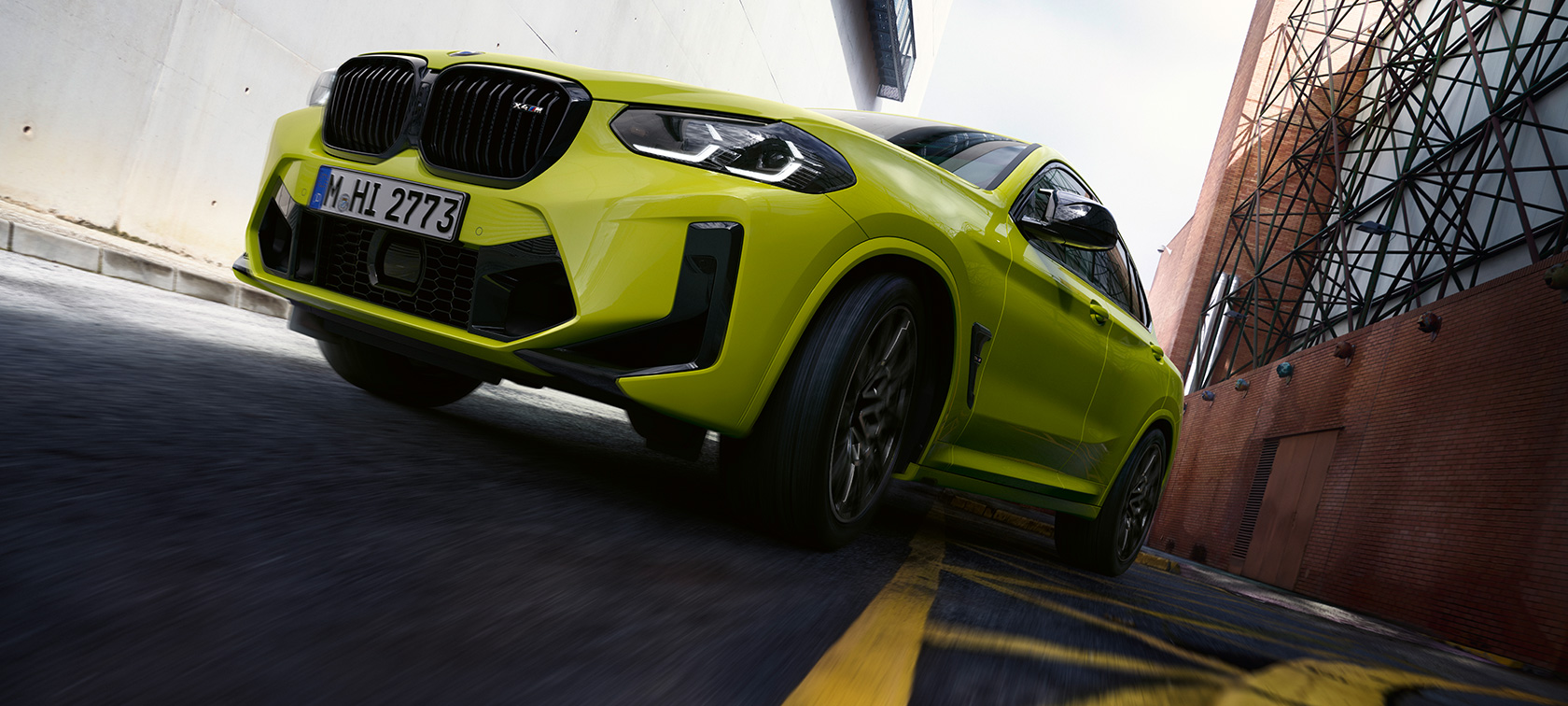 BMW X4 M Competition F98 LCI Facelift 2021 Sao Paulo Yellow three-quarter front view with bottom view driving through a canyon of houses