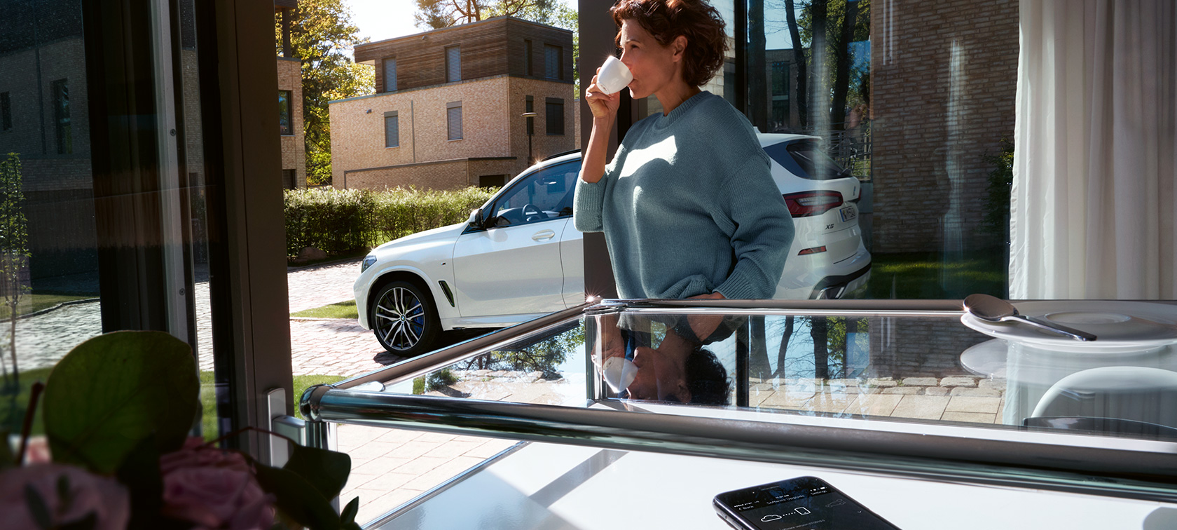 Woman drinking from cup while BMW Remote Software Upgrade updates the software of her BMW X5 